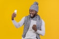 Emotional afro guy in grey winter hat taking selfie