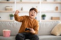 Emotional asian boy playing handheld video game at home Royalty Free Stock Photo