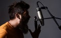 Emotional bearded man singing to condenser microphone in studio. Professional male vocalist. Music. Royalty Free Stock Photo