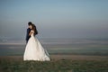 Emotional beautiful bride hugging newlywed groom from behind at