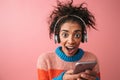 Emotional beautiful young african woman posing isolated over pink wall background listening music with headphones Royalty Free Stock Photo