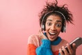 Emotional beautiful young african woman posing isolated over pink wall background listening music with headphones Royalty Free Stock Photo