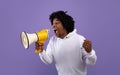 Emotional black adolescent shouting into megaphone, making announcement over violet studio background Royalty Free Stock Photo