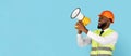 Emotional Black Builder Man Making Announcement With Loudspeaker Over Blue Background Royalty Free Stock Photo