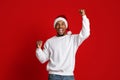 Emotional black guy in Santa hat raising hands up