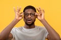 Emotional black guy touching his glasses, shouting WOW on yellow studio background, man overwhelmed with big sale Royalty Free Stock Photo