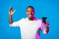 Emotional black guy winner holding joystic, isolated on blue Royalty Free Stock Photo