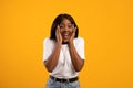 Emotional black lady in white t-shirt over yellow background