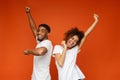 Emotional black man and woman dancing on orange