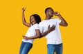 Emotional black man and woman dancing and singing on yellow