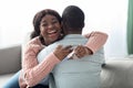 Emotional black woman with pregnancy test hugging her husband