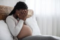 Emotional changes during pregnancy. Upset black pregnant woman covering face with hands