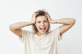 Emotional cheerful young tattooed girl smiling with opened mouth looking at camera touching hair over white background. Royalty Free Stock Photo