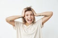 Emotional cheerful young tattooed girl smiling with opened mouth looking at camera touching hair over white background. Royalty Free Stock Photo