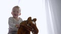 Emotional child boy delight riding on toy steed in room