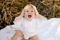 An emotional child a boy in white clothes is relaxing in the fresh air in a field and holding his hands on his head wondering Royalty Free Stock Photo