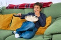 Emotional child watching tv on the sofa and eating popcorn at home, free space