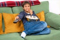 Emotional child watching tv on the sofa and eating popcorn at home, free space