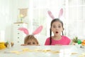 Emotional children wearing bunny ears headbands at table with Easter eggs