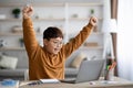 Emotional chubby asian schooler celebrating success, using notebook