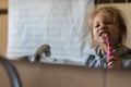 Emotional close up of a cute little girl brushing teeth with electric toothbrush.