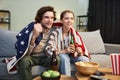 Emotional couple with American flag watching sports match at home Royalty Free Stock Photo
