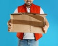 Emotional courier with damaged cardboard box on blue background. Poor quality delivery service Royalty Free Stock Photo