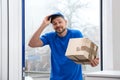 Emotional courier with damaged cardboard box . Poor quality delivery service Royalty Free Stock Photo