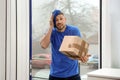 Emotional courier with damaged cardboard box. Poor quality delivery service Royalty Free Stock Photo