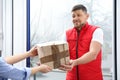 Emotional courier giving damaged cardboard box to client in doorway, closeup. Poor quality delivery service Royalty Free Stock Photo