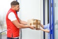 Emotional courier giving damaged cardboard box to client. Poor quality delivery service Royalty Free Stock Photo