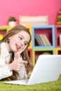 Emotional cute girl using laptop while lying on floor