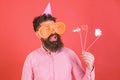Emotional diversity concept. Man with beard on cheerful face holds smiling lips on sticks, red background. Hipster in Royalty Free Stock Photo