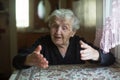 Emotional elderly woman tells gesturing sitting at a table