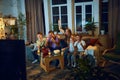 Emotional and excited man, woman and children, parents watching tv with children. Football match translation