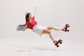 Emotional excited young girl, stylish retro waitress in american fashion style of 70s, 80s uniform rollerblade over gray Royalty Free Stock Photo