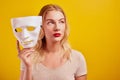 Emotional female person with white mask on yellow background. Internet fraud concept, anonymous, incognito, bipolar personality di