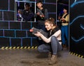 Emotional girl with laser pistol playing laser tag with multinational team