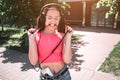 Emotional girl is standing and stretching cord from headphones and biting it at the same time. She wears glasses. Young Royalty Free Stock Photo