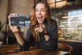 Emotional happy beautiful young pretty woman sitting in cafe indoors using mobile phone talking with friends take a selfie Royalty Free Stock Photo