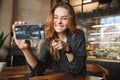 Emotional happy beautiful young pretty woman sitting in cafe indoors using mobile phone talking with friends take a selfie Royalty Free Stock Photo