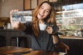 Emotional happy beautiful young pretty woman sitting in cafe indoors using mobile phone talking with friends take a selfie Royalty Free Stock Photo