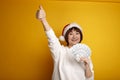 Emotional happy mature middle aged woman in red Santa Claus hat holding money showing hand ok sign on yellow background. Christmas Royalty Free Stock Photo