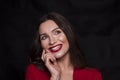 Emotional head shot portrait of a brunette caucasian woman in red dress and with red lips on black background. She smiling with Royalty Free Stock Photo