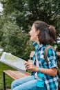 Emotional hipster young girl travels around the city. Cute brunette teen girl with a map. Traveling in summer vacation