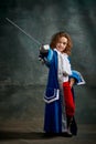 Emotional kid, little girl wearing costume of prince, musketeer and royal person posing over dark vintage style