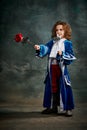 Emotional kid, little girl wearing costume of prince, musketeer and royal person posing over dark vintage style