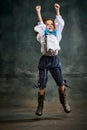 Emotional kid, little girl wearing costume of prince, musketeer and royal person posing over dark vintage style