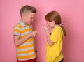 Emotional kids shout on each other and point fingers. Angry portrait of brother and sister. Negative human face