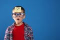 Emotional little boy with question mark on blue background, space for text Royalty Free Stock Photo